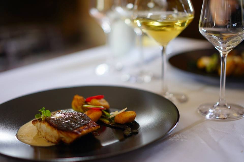 A dinner course of fish and vegetables, with a glass of white wine